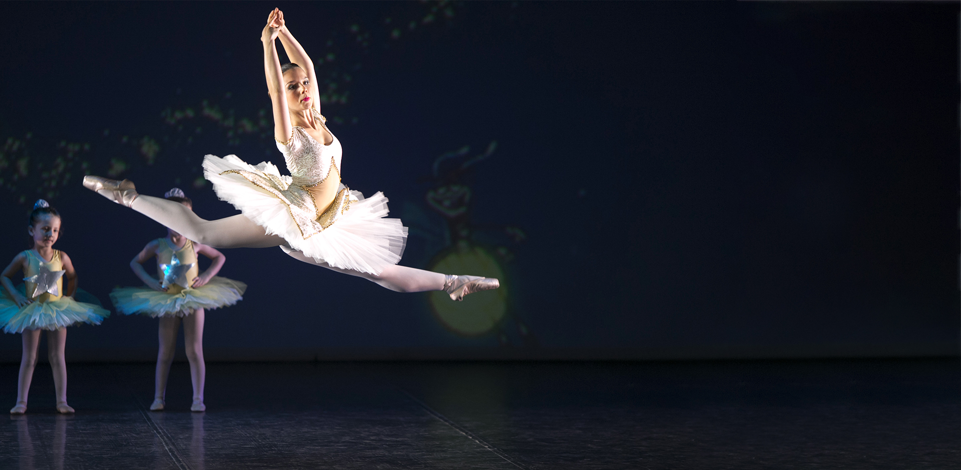 Salto di danza classica con allieve sullo sfondo